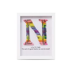 the letter n made out of colored crayons is in a white box frame