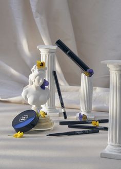 some pens are sitting on a table with other items around it, including a figurine and pencils