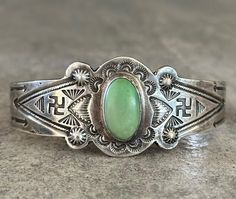 This is an amazing Old Vintage Fred Harvey Era Navajo Sterling Silver Bracelet. This eye-catching Repousse bracelet contains natural green turquoise stone. Hand stamped Whirling Log/Swastika, Tepee, Arrows, sun rays and more on both sides of the bracelet. Circa 1920's-1930's Guaranteed sterling silver. Approximate Inside measurement from tip to tip is 5-3/4" Approximate Opening measurement between tip is 1-1/4" Approximate width of the bracelet is 2-1/2"(across inside). Approximate size of the stone is 16mm L, 10mm W(measured from center of the stone). Sturdy 24.1 grams in my scale. ADJUSTABLE & STACKABLE Bracelet!!This bracelet fits from 6-1/2"to 7-1/4"size wrists. This bracelet would be a great addition to any Native American or Southwestern jewelry collection. Also this bracelet is a ti Silver Bracelet Cuff, Southwestern Jewelry, Stackable Bracelets, Bracelet Cuff, Sun Rays, Old Vintage, Green Turquoise, Sterling Silver Bracelet, Turquoise Stone