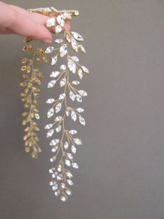 a hand is holding some gold and white brooches