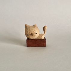 a cat figurine sitting on top of a piece of wood with one paw in the air