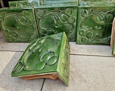 four green tiles sitting on the ground next to each other, with designs painted on them