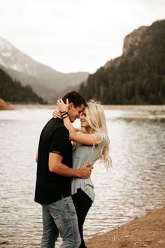 a man and woman hugging by the water