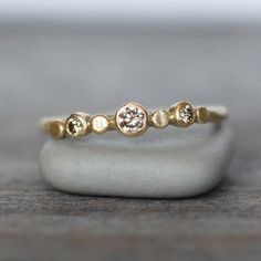 a gold ring with three different stones on it's side, sitting on top of a rock