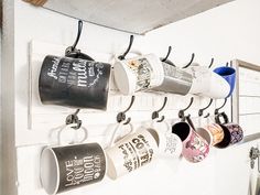 coffee mugs are hanging on the wall with hooks