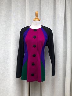 "For sale is a beautiful single breasted blazer by l.magnin in purple, fuchsia, green colors and black sleeves,  button down with big fabric wrapped black buttons, the shoulders are padded. 100% Acrylic.  Marked size 10 Good vintage condition!  Measurements (flat): shoulder to shoulder approx 14\" Armpit to armpit: 17\" sleeve length approx: 20\" Overall length: 28\"" Fitted Black Color Block Outerwear, Purple Long Sleeve Cardigan With Button Closure, Fitted Multicolor Outerwear With Button Closure, Purple Workwear Blazer With Button Closure, Fitted Fall Outerwear With Color Block, Purple Blazer For Work, Purple Cardigan For Workwear In Fall, Purple Cardigan For Workwear, Fall Season, Purple Cardigan For Fall Workwear