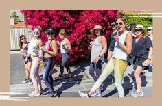 a group of women standing next to each other in front of a pink flower bush