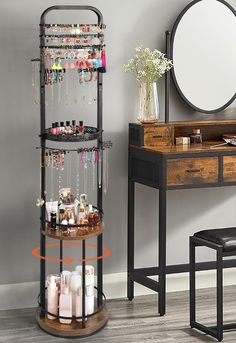 a round shelf with jewelry on it in front of a mirror and table next to a stool