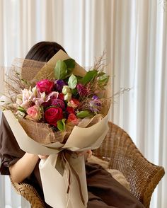 a woman sitting in a chair holding a bouquet of flowers