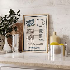 a coffee menu hangs on the wall next to a potted plant and two mugs