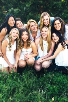 a group of young women posing for a photo together in the grass with their arms around each other