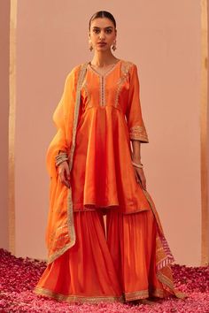 Tangerine orange peplum anarkali with tilla, patra, zari thread embroidery. Paired with gharara and geometric hand block print dupatta.
Components: 3
Pattern: Embroidery
Type Of Work: Tilla, patra, zari thread
Neckline: V neck
Sleeve Type: Three quarter
Fabric: Kurta: Silk Chanderi, Gharara: Georgette, Dupatta: Silk Organza
Color: Orange
Other Details: 
Tiered gharara
Gota lace embroidered hem
Sheer printed dupatta
Occasion: Sangeet - Aza Fashions Designer Resham Embroidery Sharara For Diwali, Floor-length Zari Work Sharara For Festivals, Festival Floor-length Sharara With Zari Work, Semi-stitched Sharara For Designer Wear Diwali, Festive Floor-length Sharara In Dola Silk, Dola Silk Sharara With Zari Work, Floor-length Sharara With Pallu For Eid, Festive Anarkali Style Unstitched Sharara, Festive Anarkali Sharara Unstitched