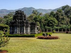 a large stone structure sitting in the middle of a lush green field next to trees