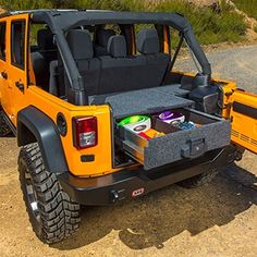 the back end of a yellow jeep with its trunk open and coolers in it