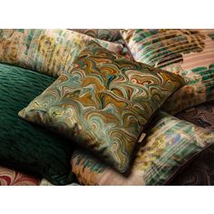 a pile of pillows sitting on top of a bed covered in green and brown blankets