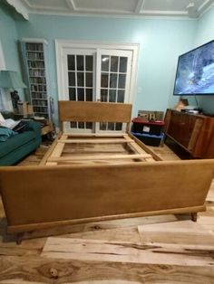 a wooden bed frame sitting on top of a hard wood floor in a living room