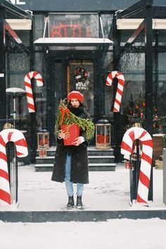 a woman standing in front of a store with candy canes