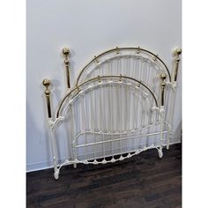 a white iron bed frame with gold posts and two candles on each side, against a wall