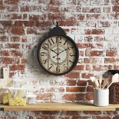 a clock on a brick wall above a shelf with utensils and other kitchen items