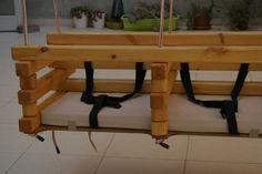 a wooden bench with ropes hanging from it's sides and two cushions on the bottom