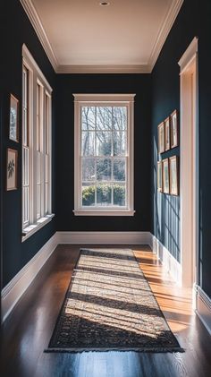 an empty room with blue walls and wooden floors, framed pictures on the wall, and a large rug