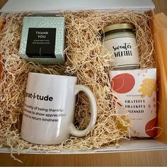 an open box containing two coffee mugs and a tea bag