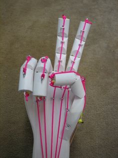 a hand made out of white paper with pink stringing on the fingers and wrist