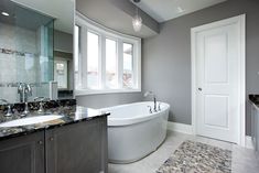 a bathroom with a large tub and two sinks in it's center, surrounded by marble counter tops