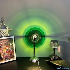 a green lamp sitting on top of a desk next to a framed photo and an art piece