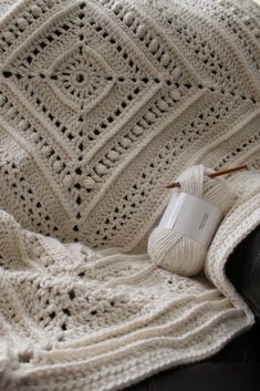 a white crocheted blanket sitting on top of a couch