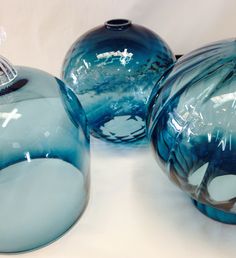 three blue glass vases sitting next to each other