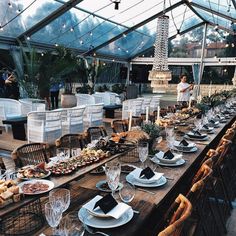 a long table is set up with plates and silverware for an outdoor dinner party