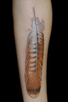 an orange and white feather tattoo on the leg