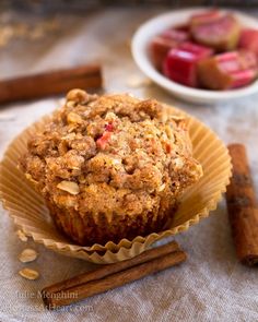 a muffin sitting on top of a table next to cinnamon sticks