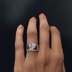 a woman's hand with a diamond ring on top of her finger and an engagement band