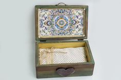 an open wooden box with fabric in it on a white wall next to a heart - shaped pillow