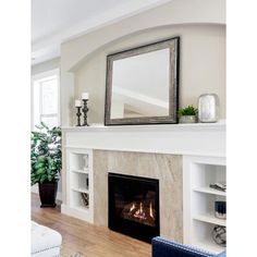 a living room with a fire place and mirror on the fireplace mantel above it