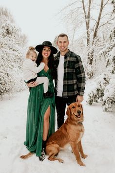 a man, woman and child standing in the snow with a dog