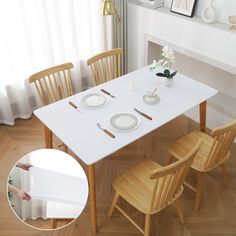 a white table with four chairs and plates on it, in front of a window