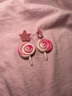 two pink and white lollipop earrings on top of a pink sheet with stars