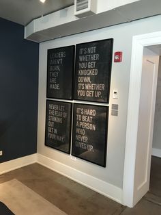 three black and white posters hanging on the wall in a room with carpeted flooring