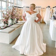 a woman in a white dress standing next to some dresses