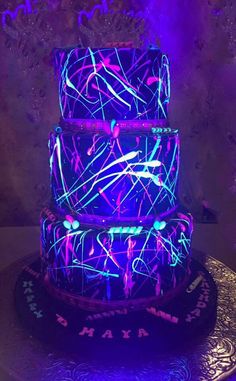 a three tiered cake with purple and blue lights on it's top layer