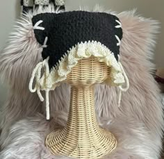 a black and white hat sitting on top of a wicker mannequin