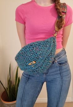 a woman is holding a crocheted purse in her left hand and wearing blue jeans