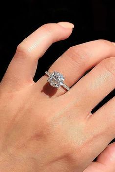 a woman's hand with a diamond ring on top of her finger and the other hand holding an engagement ring