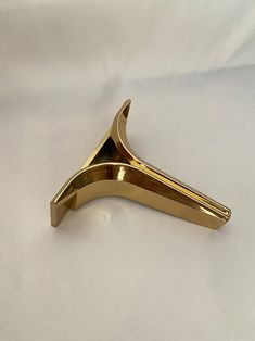 a gold metal object on a white surface