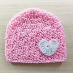 a pink crocheted hat with a white heart on it