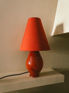 a red lamp sitting on top of a white shelf