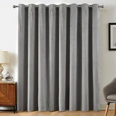 a living room with grey curtains and a chair